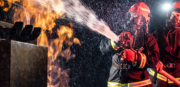 Firemen extinguishing fire with fire hose