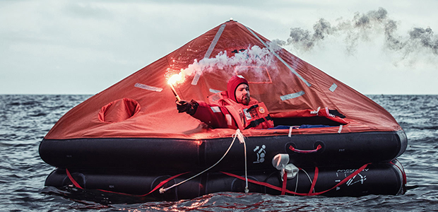 Man in Marine liferaft holding flare